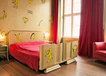 room with a golden bed and red velvet curtains